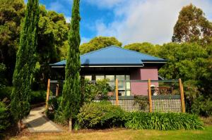 a pink house with a blue roof in a garden at Waterfall Cottages in Margaret River Town
