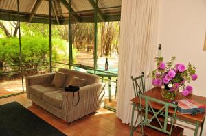 a living room with a couch and a table with flowers at Waterfall Cottages in Margaret River Town +12 photos