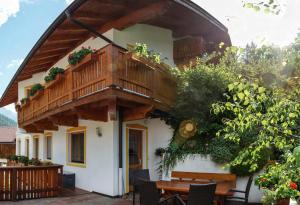 Casa con balcón de madera y mesa en Haus Ferchl, en Neustift im Stubaital