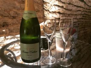 Una botella de vino y dos copas en una mesa. en LE GOLURET Chambres & Table d'hôtes - Espace Bien Être en Couvignon