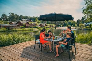 a family sitting at a table under an umbrella at EuroParcs Brunssummerheide in Brunssum