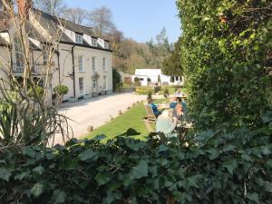 a group of people sitting in chairs in a garden at Combe House Hotel in Holford