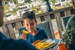 a young child sitting at a table with a plate of food at EuroParcs Brunssummerheide in Brunssum