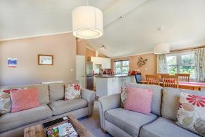 a living room with two couches and a kitchen at Poppy Lodge in Sherborne