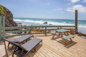 a deck with two chairs and a picnic table on the beach at Beachcomber's Cottage in Millbrook