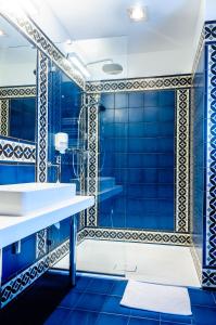 La salle de bains est pourvue de murs carrelés bleus et d'une douche. dans l'établissement Hotel Hugo Business & Spa, à Kędzierzyn-Koźle