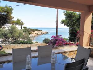 a table with chairs and a view of the ocean at Archos Seafront Apartments in Porto Heli