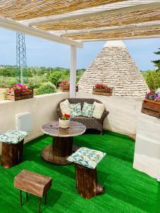 a patio with a table and chairs on green grass at Trulli Pietra Viva in Alberobello