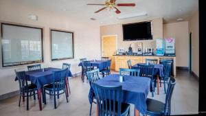 a restaurant with blue tables and chairs and a flat screen tv at OYO Hotel Yoakum West in Yoakum