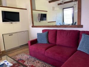 ein rotes Sofa im Wohnzimmer mit Spiegel in der Unterkunft Lussuoso appartamento nella magia del lago d'Orta in Orta San Giulio