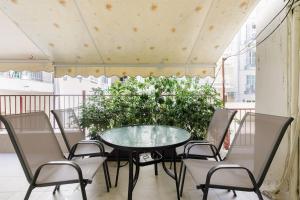 einen Tisch und Stühle auf einem Balkon mit einer Pflanze in der Unterkunft Lassani cozy and quiet, 2 bedroom apartm with spacious balcony in Thessaloniki