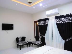 a room with two chairs and a bed and a tv at Travelodge Guesthouse in Islamabad