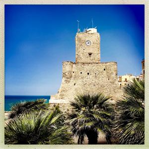 un vieux bâtiment avec une tour d'horloge à côté de l'océan dans l'établissement TERMOLI, NEL CUORE DEL CENTRO STORICO, à Termoli