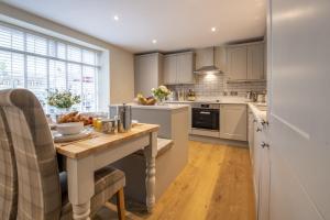 a kitchen with white cabinets and a wooden table at 2 West End in Northallerton