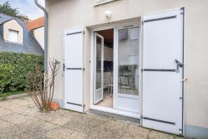 two doors open to a house with a patio at Vacances familiales dans cette maison à Pornichet in Pornichet