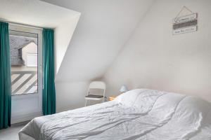 a bedroom with a bed and a chair and a window at Vacances familiales dans cette maison à Pornichet in Pornichet