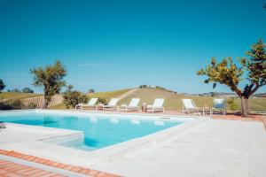 a swimming pool with two lounge chairs and a hill at Villa Roberto in Monte San Giusto