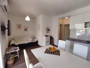eine Küche und ein Wohnzimmer mit einem weißen Tisch und Stühlen in der Unterkunft Apartman Portorus in Lastovo