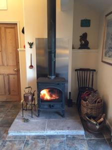 a wood stove in a room with a refrigerator at The Stable with cosy logburner in Wrexham