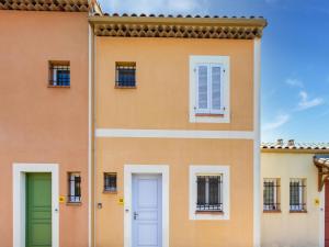 un bâtiment orange avec une porte et des fenêtres vertes dans l'établissement Comfortable holiday home with swimming pool, à Arles