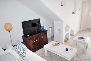 a living room with a white couch and a flat screen tv at Sea and Sun beach house at Platis Gialos in Platis Gialos
