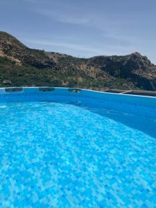 une grande piscine bleue avec une colline en arrière-plan dans l'établissement Cortijo La Miel, à Cádiar