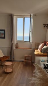 Una sala de estar con una gran ventana y un sofá. en Villa Mignon grand studio vue Mer, en Mers-les-Bains