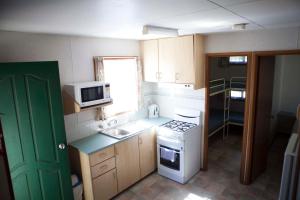 a small kitchen with a stove and a microwave at Strayleaves Caravan Park in Shepparton