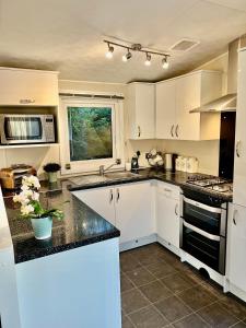 a kitchen with white cabinets and black counter tops at New Forest Hideaway- Self Catering Accommodation in Newbridge