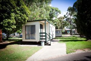 a small green building with a porch on a street at Strayleaves Caravan Park in Shepparton