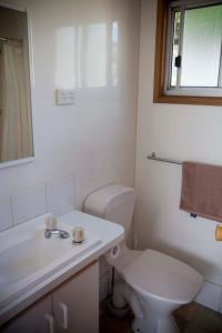 een witte badkamer met een toilet en een wastafel bij Strayleaves Caravan Park in Shepparton