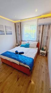 - une chambre dotée d'un grand lit avec des draps bleus et une fenêtre dans l'établissement Siófok Private House, à Siófok
