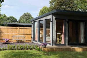 a small black shed with a table in a yard at Self Contained Garden Studio with stunning views in Sissinghurst