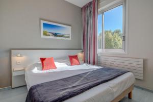 Schlafzimmer mit einem Bett mit roten Kissen und einem Fenster in der Unterkunft Hôtel Miléade Méditerranée - Port-Fréjus in Fréjus