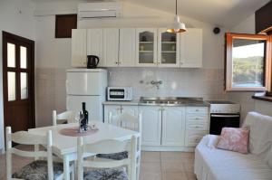 eine Küche mit weißen Schränken sowie einem weißen Tisch und Stühlen in der Unterkunft Romantic Boxavia in Božava