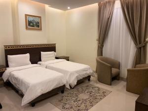 a hotel room with two beds and a chair at Al Safiah Hotel in Al Madinah