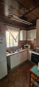kuchnia z białymi szafkami i białą lodówką w obiekcie La Casa del Rio w mieście Casabermeja