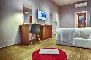 a bedroom with a bed and a desk and a red rug at Quaint Boutique Hotel Xewkija in Xewkija