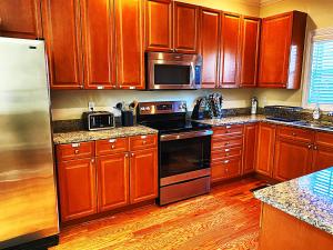 una cocina con armarios de madera y electrodomésticos de acero inoxidable en *Stylish* Luxury Suite Near Historic Downtown, en Charleston