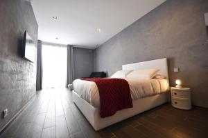 a bedroom with a white bed with a red blanket at Quaint Boutique Hotel Xewkija in Xewkija