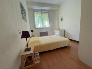 a bedroom with a bed and a table with a lamp at La Résidence - n° 02 - T2 classé** in Gréoux-les-Bains