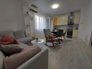 Apartman Nora في Ubli: غرفة معيشة مع أريكة وكراسي ومطبخ