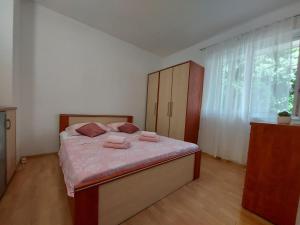 Schlafzimmer mit einem Bett mit rosa Bettwäsche und einem Fenster in der Unterkunft Apartman Nora in Ubli