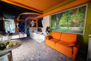 1 dormitorio con sofá naranja y una gran pintura en la pared en Garda fantasy green jacuzzi sauna piscina, en Desenzano del Garda