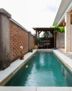 塞隆貝拉納克的住宿－Surya Lombok Accommodation，后院的游泳池,有砖墙