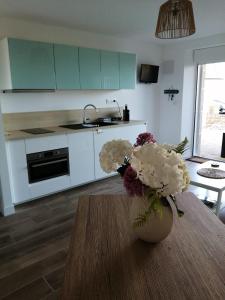 a kitchen with a table with a vase of flowers on it at L'Échappée Bleue, vue mer in Binic