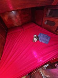 a bed with a red sheets and flowers on it at Barca a vela d’epoca Emibel in Cannigione