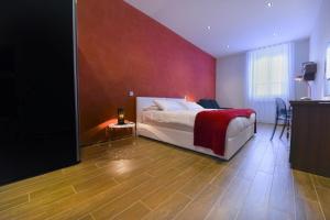 a bedroom with a bed with a red wall at Quaint Boutique Hotel Xewkija in Xewkija