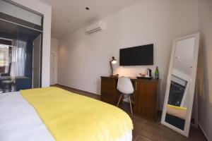 a bedroom with a yellow bed and a television at Quaint Boutique Hotel Xewkija in Xewkija