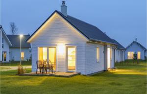 a small white house with chairs in a yard at Lovely Home In Ostseeresort Olpenitz in Olpenitz